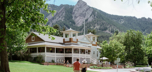 two couple walking in front of the The Colorado Chautauqua in Boulder Colorado with mountains in the background