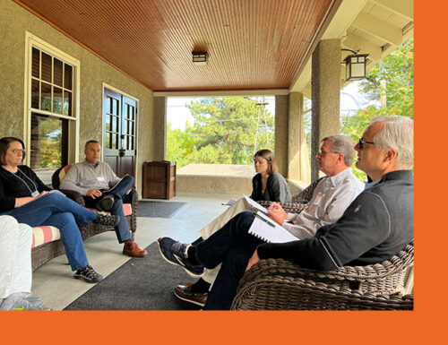 Group of five people sitting on a front porch outside discussing engineering topics together